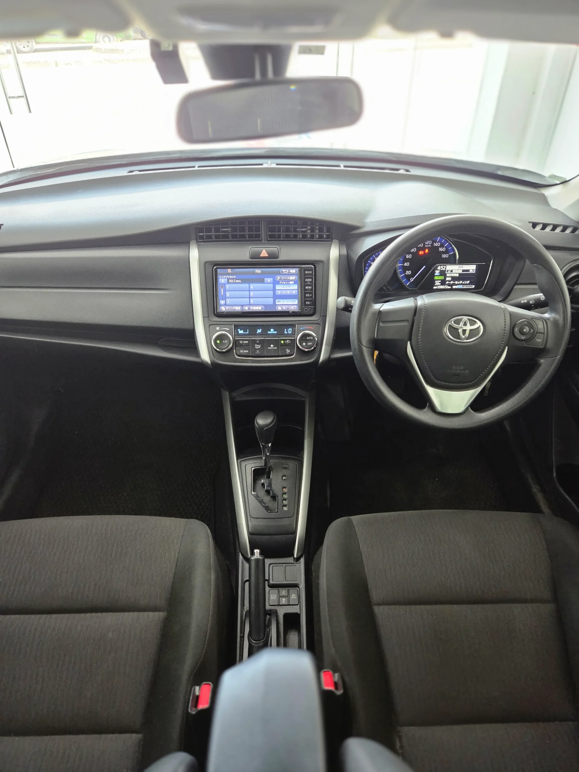 Spacious black fabric interior of the 2018 Toyota Corolla Fielder Hybrid showing the dashboard and key-start ignition.