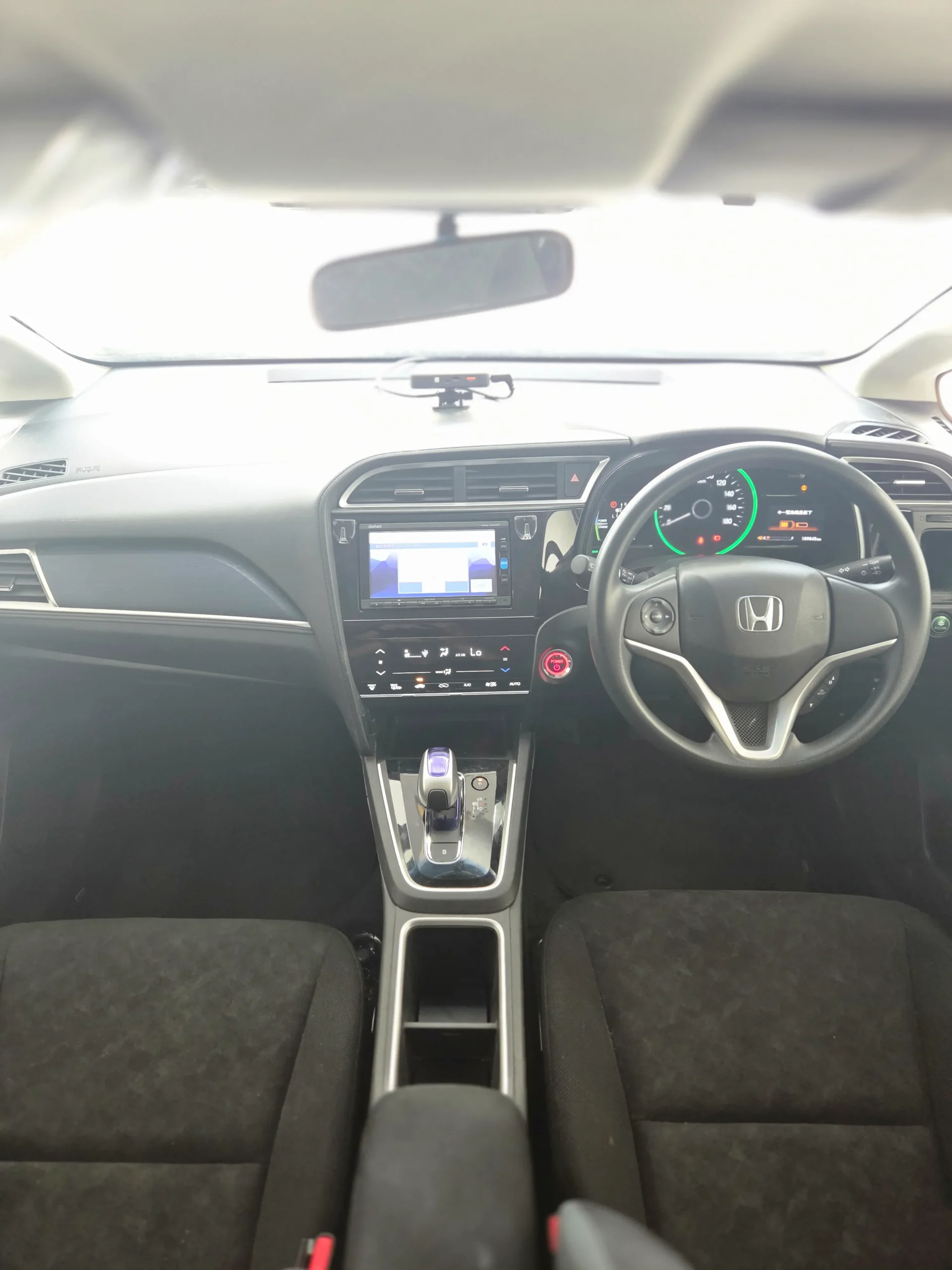 Spacious cabin of the 2018 Honda Shuttle Hybrid showing the push-start button, steering controls, and versatile seating.