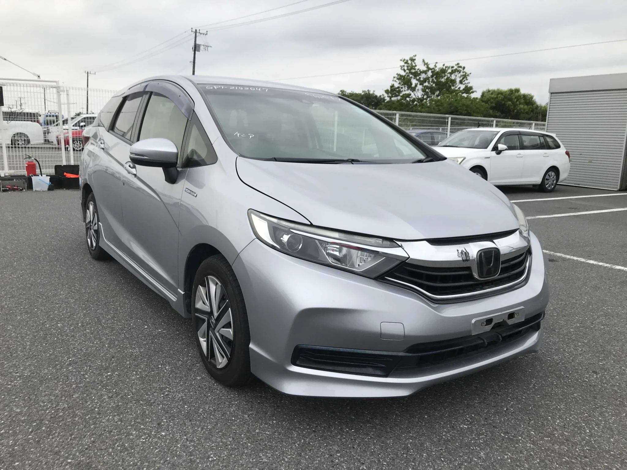 Sleek metallic silver Honda Shuttle Hybrid 2019 New Shape wagon showcasing its redesigned chrome-trimmed front grille, sharp Xenon LED headlights, and modern bumper styling at Mundiya International.